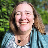 Smiling woman in front of green trees