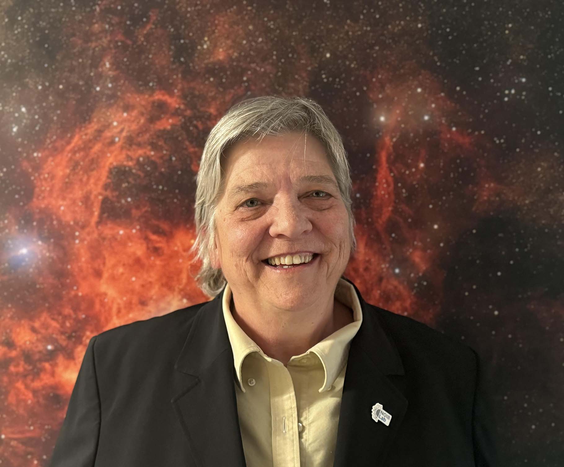 Headshot of Lori Allen smiling in front of red starry background.