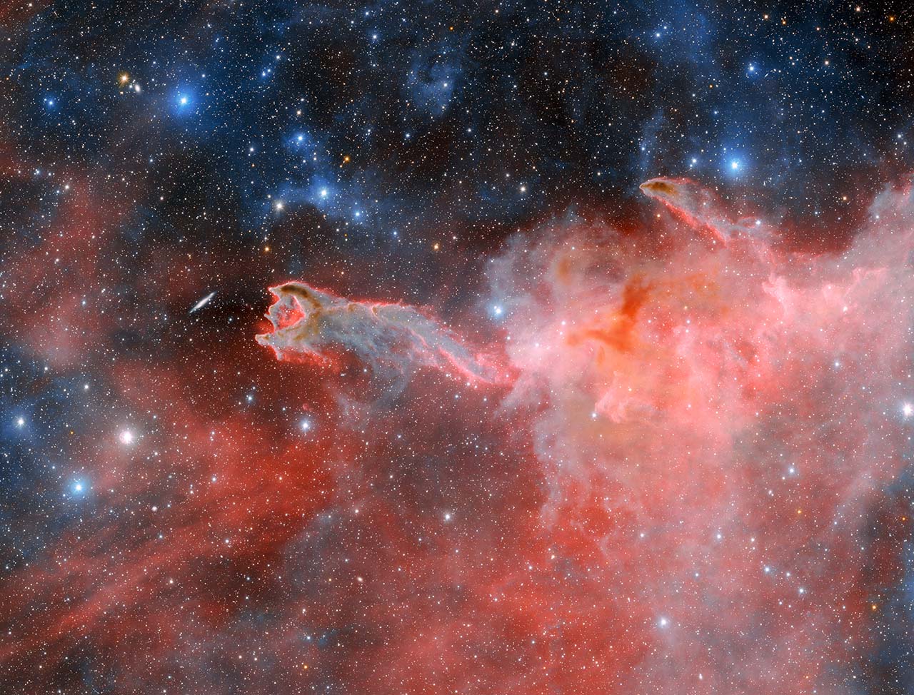 Dark Energy Camera Images Cometary Globule CG 4. Stars in various brightness shine throughout the image which is red and pink on the bottom 2/3 and black along the top.