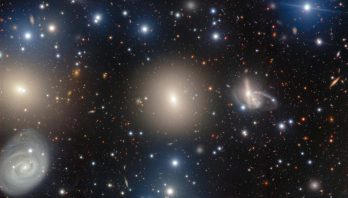 NGC 1270: A Galactic Archipelago is shown as glittering stars on a deep black background with large fuzzy halos of yellow