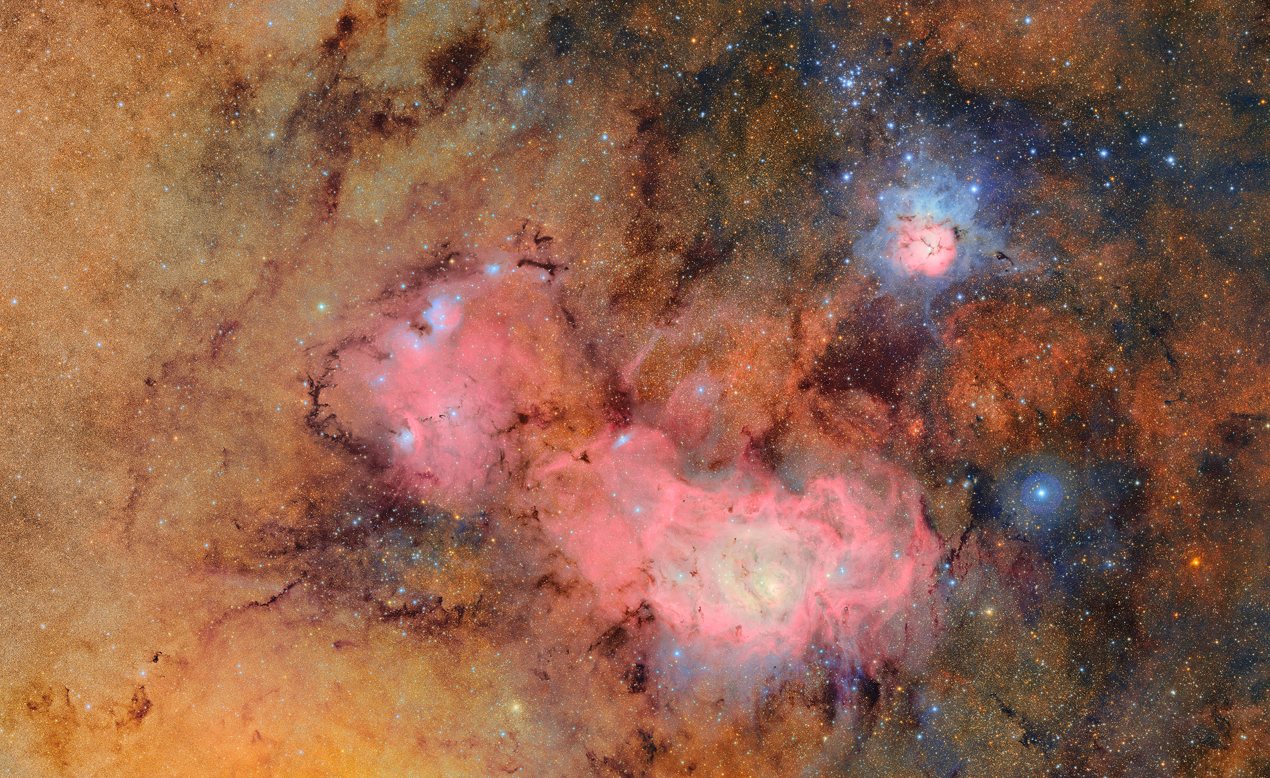 An image densely filled with stars gas and dust in gold pink and blue.