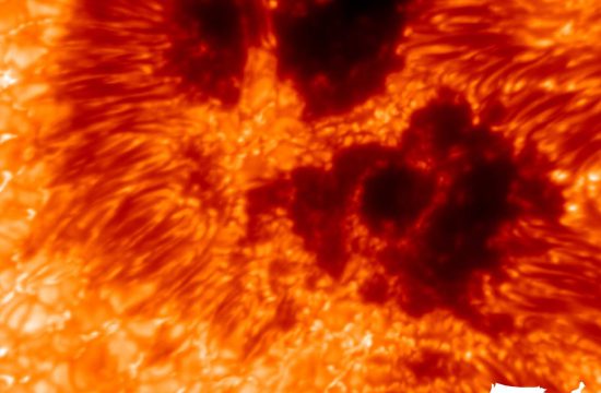 Undulating waves of gold, orange and red fill this image. Dark black areas are surrounded by deep red and orange indicating sunspots.