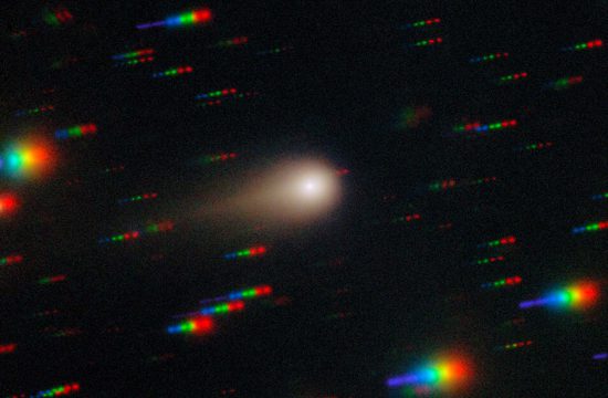 A glowing ball with a gold halo and tail streaks to the right in the center of this image. The black background is cover with rainbow colored streaks throughout the image.