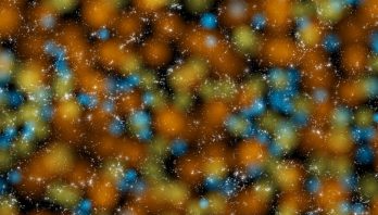 A scattering of white points, each representing a galaxy. Fuzzy circles colored orange, yellow-green, and blue show voids of various sizes where there are few galaxies.