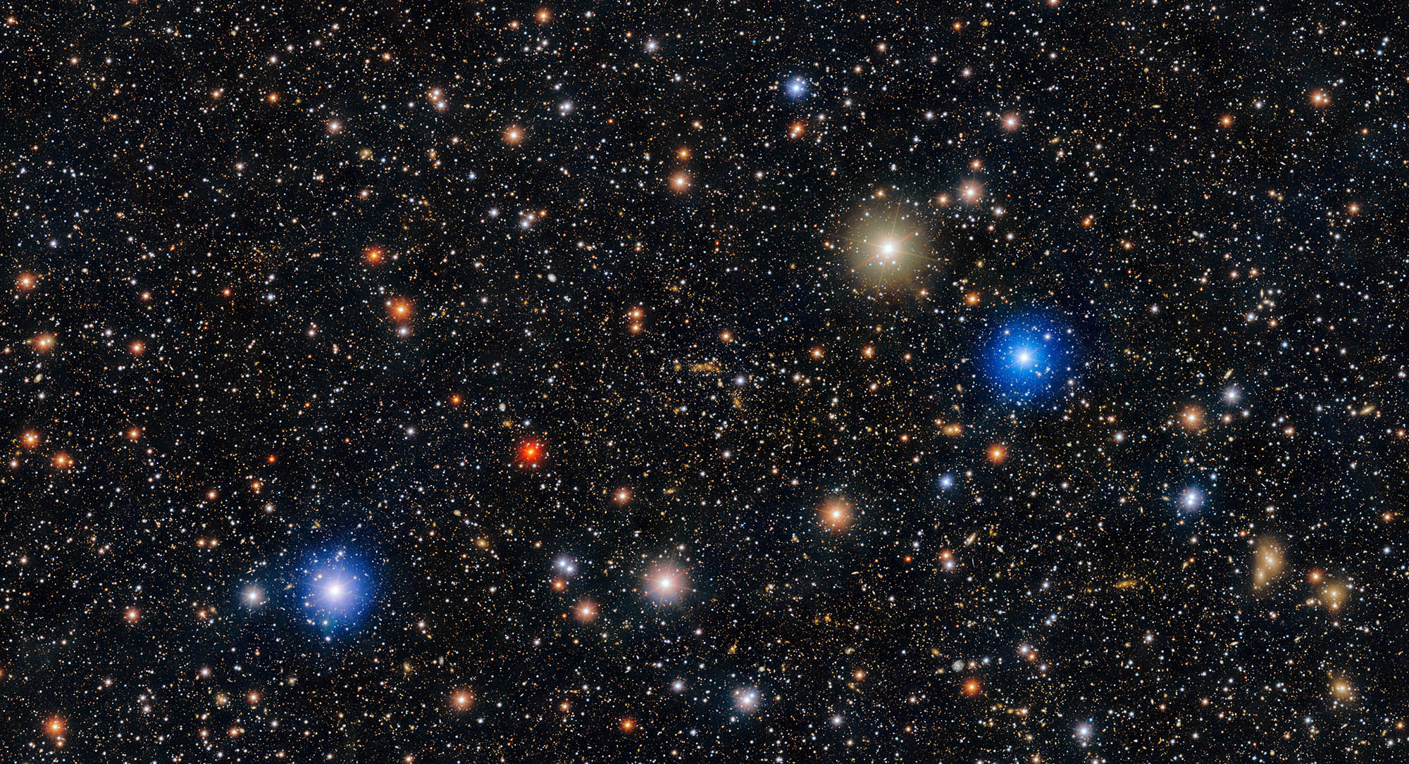 A black background is filled with stars -small and large glowing white, red, yellow and blue.