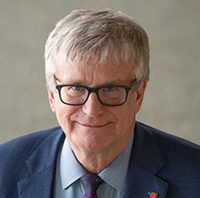 Grey haired man in a suit and glasses