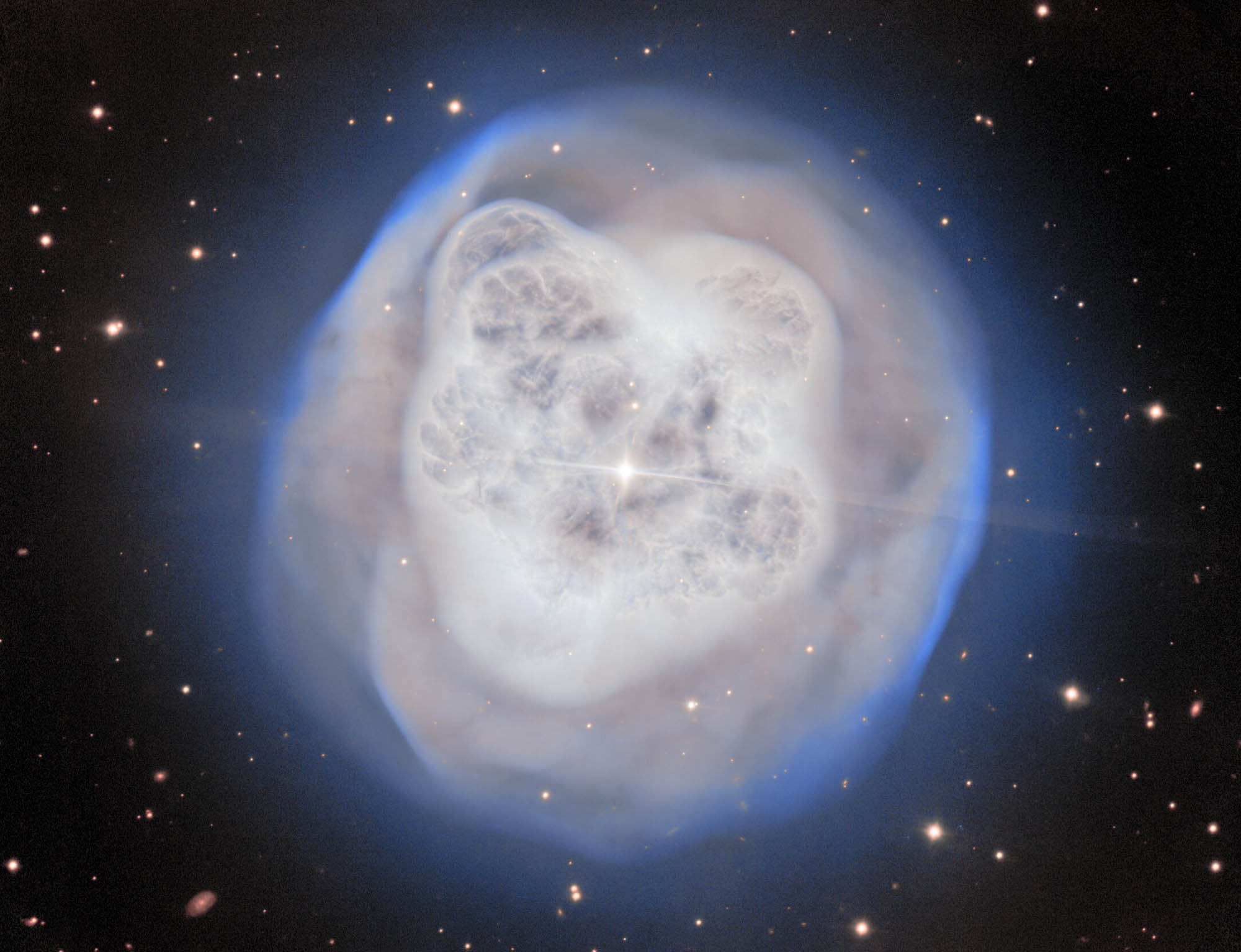 A large white and tan fuzzy object sits on a dark background dotted with stars. The object is convoluted with protruding areas and a bright white star in the center.