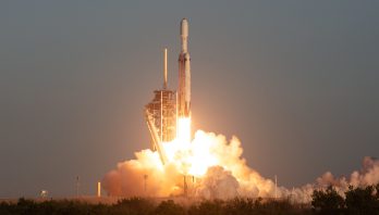 Rocket blasting off of the launchpad with a large plume of smoke beneath it.