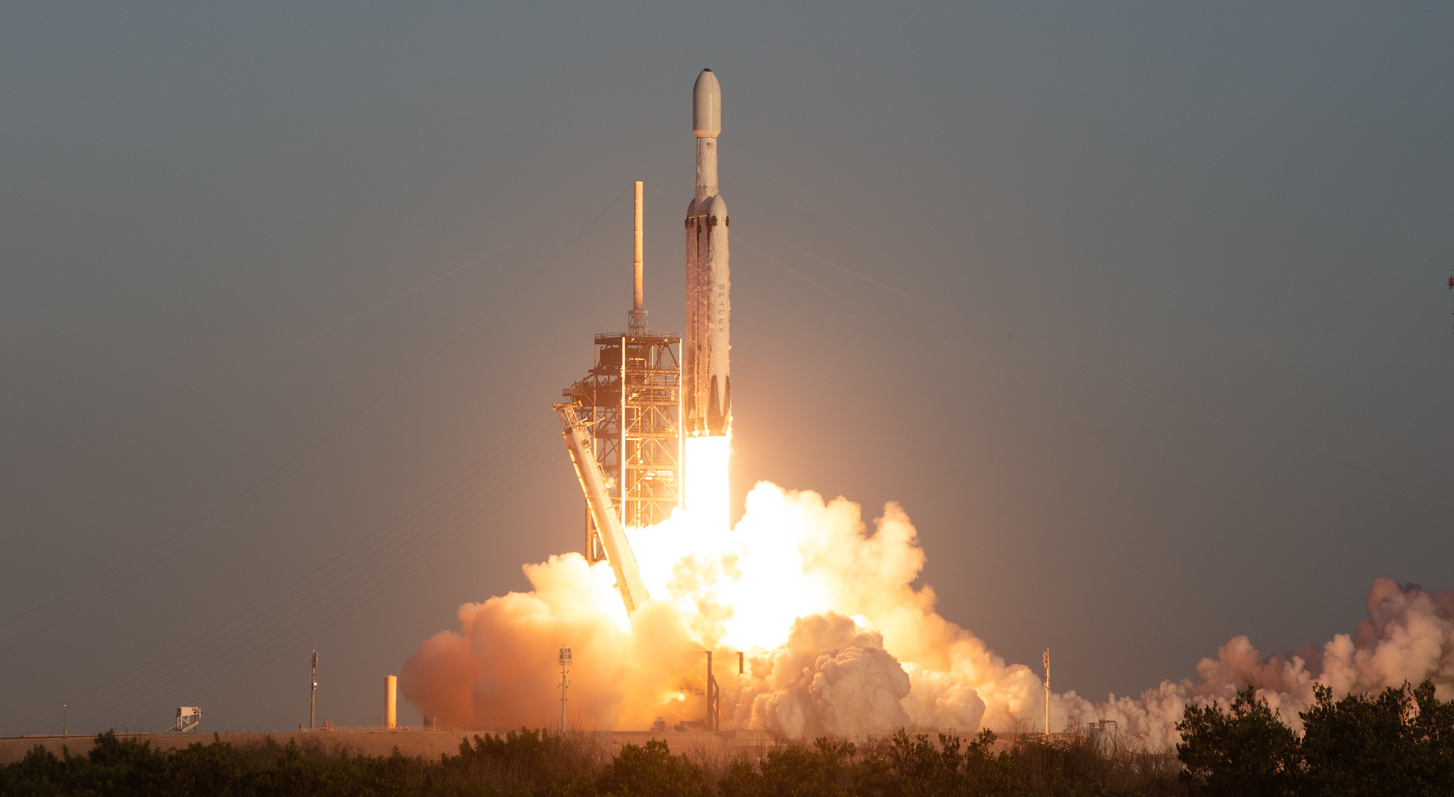 Rocket blasting off of the launchpad with a large plume of smoke beneath it.