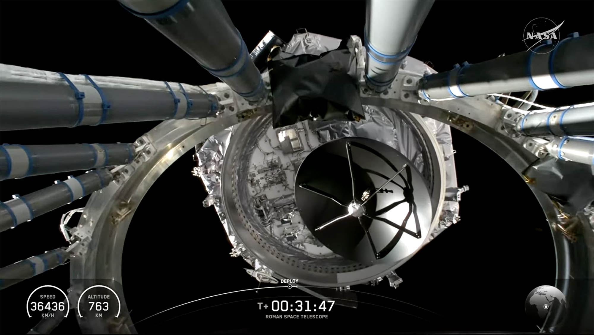 Center of the image shows the silver outside of a telescope being released from a rocket against a black sky.
